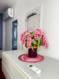 a vase with pink flowers on a table with a remote control at Casa Vacanze Maridy in Naples
