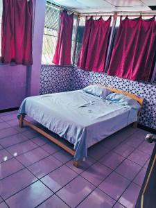 Cama en habitación con suelo y ventanas de color púrpura en Casa sanacion Elixir, en Pucallpa