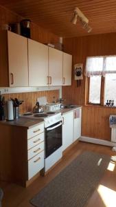 La cuisine est équipée de placards blancs et d'un four avec plaques de cuisson. dans l'établissement Cosy cabin near Hraunfossar, à Reykholt