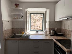 a kitchen with a sink and a window at Apartman Kalinić in Ston