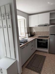 uma cozinha com armários brancos e um forno com placa de fogão em Apartman Kalinić em Ston