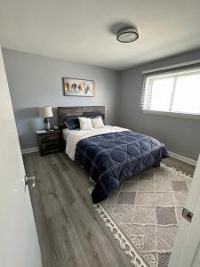 a bedroom with a bed with a blue blanket and a window at Spotless 4 Bedrooms 4 Beds Sleep 8 in Winnipeg in Winnipeg