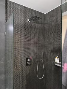 La salle de bains est pourvue d'une douche et de carrelage noir. dans l'établissement Cosy room in Morden apartment, à Luxembourg