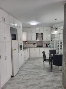 a kitchen with white cabinets and a table and chairs at Al lado del mercado in Vinarós
