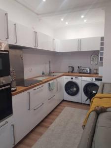 a kitchen with white cabinets and a washer and dryer at Wee Harbour View in Millport