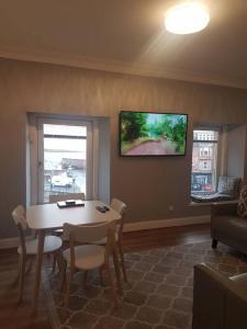 uma sala de estar com uma mesa e uma televisão na parede em Wee Harbour View em Millport
