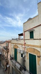 an apartment building with green doors and a balcony at Zohra in Castellammare del Golfo