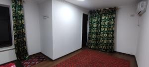 Habitación con alfombra roja, cortinas y puerta en Diyor Hostel, en Bukhara