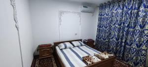 1 dormitorio con cama y cortina azul y blanca en Diyor Guest house, en Bukhara