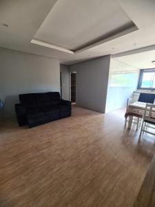 sala de estar con sofá negro y suelo de madera en Casa Angra vista pro mar, en Angra dos Reis