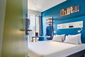 a bedroom with a white bed and a blue wall at ibis budget Saint-Ouen-l'Aumône in Saint-Ouen-lʼAumône