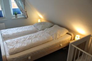 a bed with white sheets and pillows in a room at Huus Diekkieker in Nordstrand