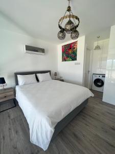 a bedroom with a large white bed and a chandelier at Hermes Penthouse Sea Sky & Mountains in Akanthou +51 photos