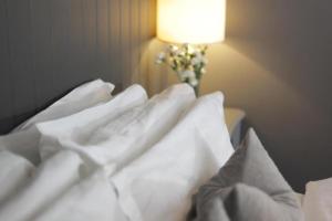 Una cama con sábanas blancas y un jarrón con flores. en The Old Talbot Hotel Milton Keynes en Potterspury