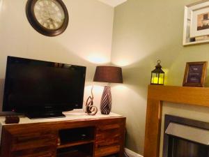 a flat screen tv sitting on a dresser with a clock at A single-bed room with a guest lounge in Cheltenham