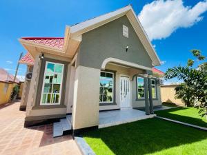 una pequeña casa con un césped verde delante de ella en Revara Home en Dodoma