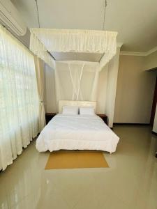 Revara Home في دودوما: غرفة نوم بسرير أبيض مع مظلة