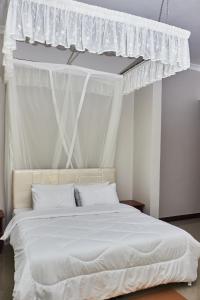 a bedroom with a white bed with a canopy at Revara Home in Dodoma