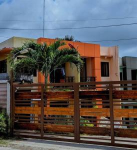 a fence with a palm tree in front of a house at 2BR 2BT home with pool between Tagbilaran and Panglao in Dauis