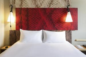 a bed with two white pillows and two lights at Hotel ibis Rennes Centre Gare Sud in Rennes