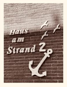 諾德代希的住宿－Hotel Pension garni Haus am Strand 2，砖墙上的标志,鸟儿飞过墙