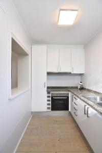 eine weiße Küche mit weißen Schränken und einer Spüle in der Unterkunft Apartament Luna in L'Escala