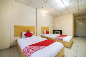 a bedroom with two beds with red and white sheets at Hotel River Inn in Butterworth