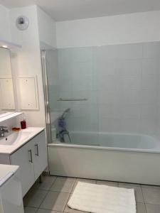 Baño blanco con bañera y lavamanos en Jolie T2 proche de Paris et du Stade De France, en Pierrefitte-sur-Seine