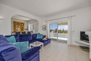 uma sala de estar com um sofá azul e uma televisão em Villa Farol by Villa Plus na Praia do Carvoeiro