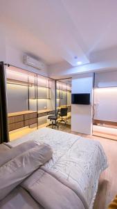 een slaapkamer met een bed, een bureau en een televisie bij Menara One Hotel by Menara Santosa in Kartosuro