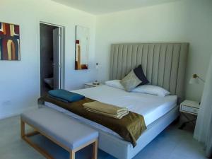 1 dormitorio con cama blanca grande y taburete en O Kouche Soley - Duplex Pied Dans L'eau, en Cap Malheureux