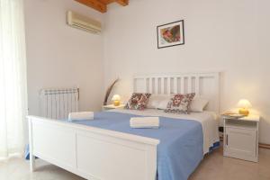 Dormitorio blanco con cama con sábanas y almohadas azules en Casa Vacanza Nì Rosa, en Cefalú