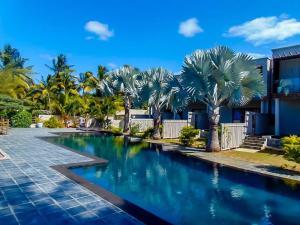 una piscina frente a una casa con palmeras en O Kouche Soley - Duplex Pied Dans L'eau, en Cap Malheureux