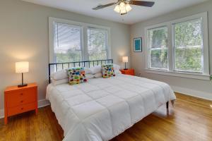 a bedroom with a white bed and two windows at Vibrant Fayetteville Home - Walk Downtown! in Fayetteville