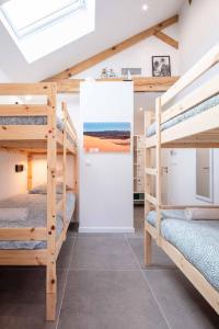 Cette chambre comprend 3 lits superposés et une porte. dans l'établissement Ted Surf House, à Capbreton