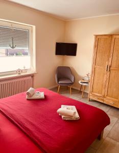 a bedroom with a red bed with two towels on it at Hotel Pension garni Haus am Strand 2 in Norddeich