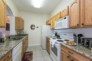 una cocina con electrodomésticos blancos y armarios de madera en LUXURIOUS CONDO - JUST 2 MILES FROM DISNEY #404 en Orlando