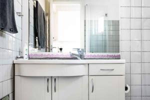 un bagno bianco con lavandino e specchio di Bornholm Holiday Apartment With Sea View ad Allinge Altre 12 foto