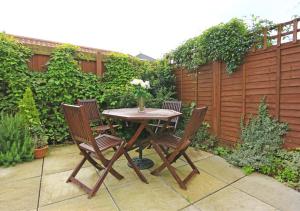 a wooden table with two chairs and a vase of flowers at Scholars Cottage in Reydon