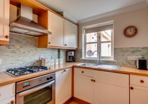 a kitchen with white cabinets and a stove and a window at Scholars Cottage in Reydon +5 photos
