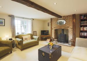 a living room with a fireplace and a couch and chairs at Walnut Tree Cottage in Mildenhall