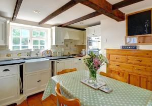 een keuken met een tafel met een vaas met bloemen erop bij Walnut Tree Cottage in Mildenhall