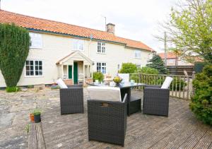 a patio with a table and chairs on a deck at Walnut Tree Cottage in Mildenhall