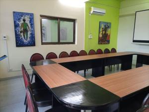 - une salle de réunion avec des tables et des chaises en bois dans l'établissement Oasis Lawafossi, à Bobo-Dioulasso