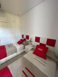 1 Schlafzimmer mit 2 Betten mit roten und weißen Kissen in der Unterkunft Lilacs Garden Cabo in Mʼdik