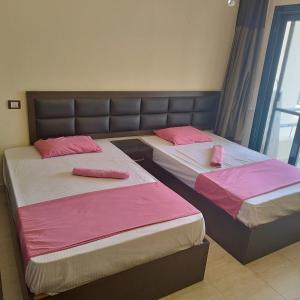 沙姆沙伊赫的住宿－Juliee House-Criss Resort-Naama Bay，配有粉红色床单的客房内的两张床
