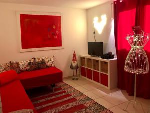 ユゼスにあるVilla Romaine & Spa à Uzèsの赤いソファとテレビのあるリビングルーム