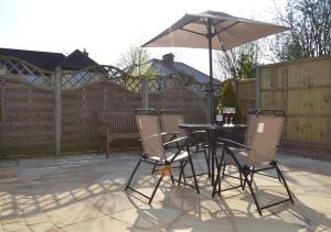 a table and chairs with an umbrella on a patio at The Cartlodge in Sudbury