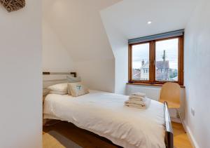 a white bedroom with a bed and a window at The Cartlodge in Sudbury