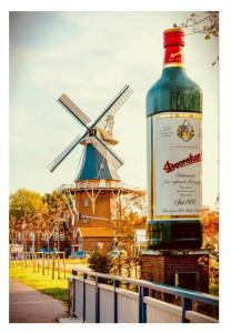 a bottle of wine sitting on a fence with a windmill at Hotel Pension garni Haus am Strand 2 in Norddeich
